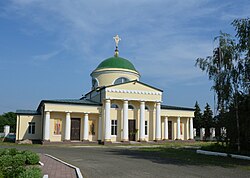 A yellow neo-classicist church with a green cupola