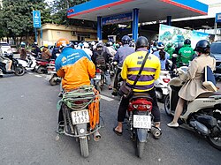 People on motorcycles crowded inside a petrol station in a Vietnamese city